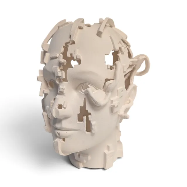 An unglazed white porcelain head, seen at three-quarter view, broken into a pixelated, glitch-like pattern: square cutouts open through the face and scalp, and blocky fragments jut out from its surface. Tube-like cords loop from the right eye up and around the side of the head.